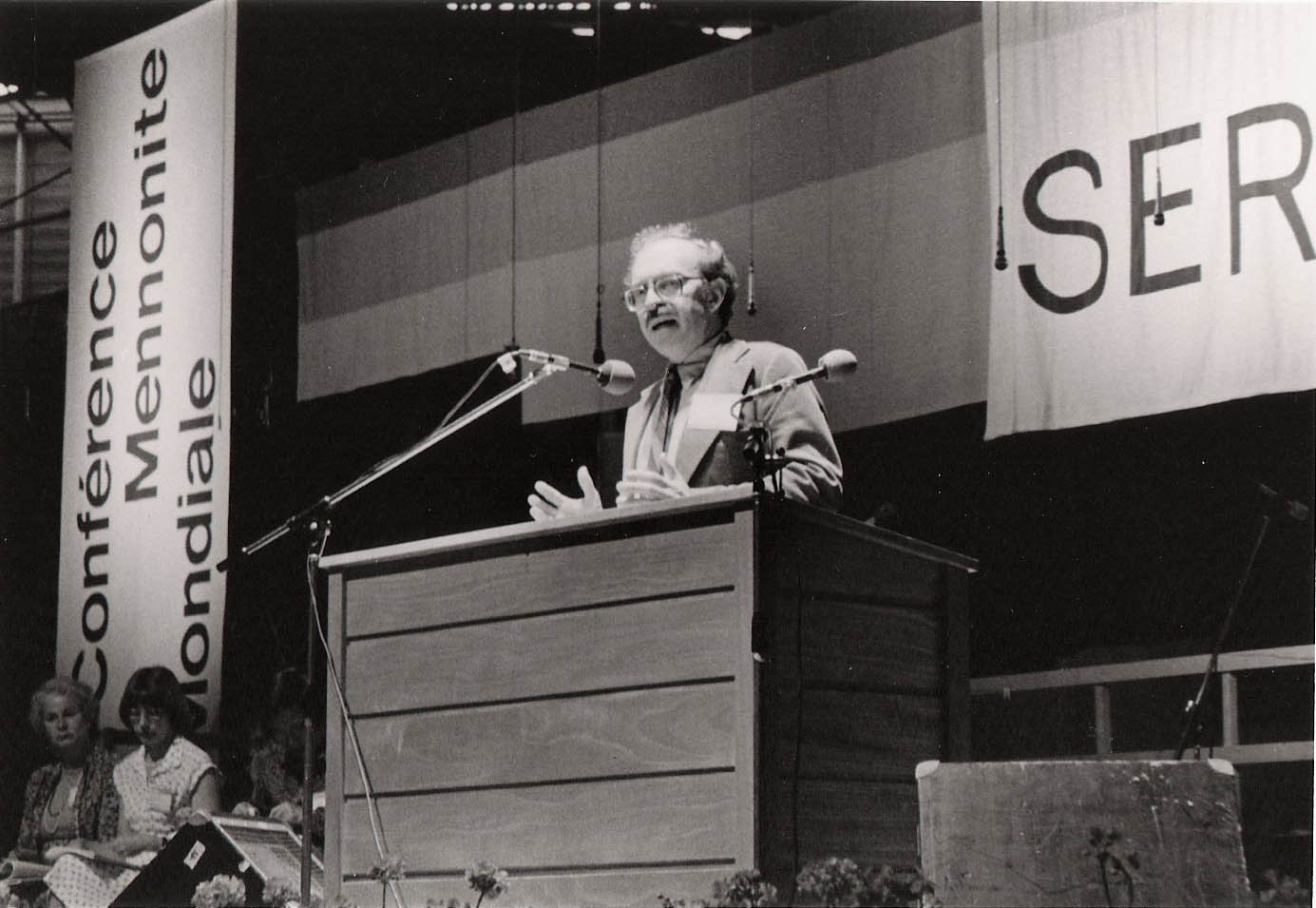 Ronald J. Sider stands behind a podium while making a speech